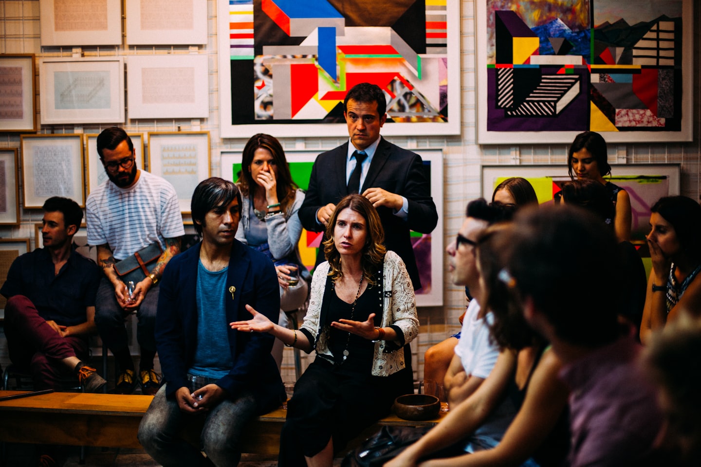 Persone in una galleria d'arte che discutono di quadri.