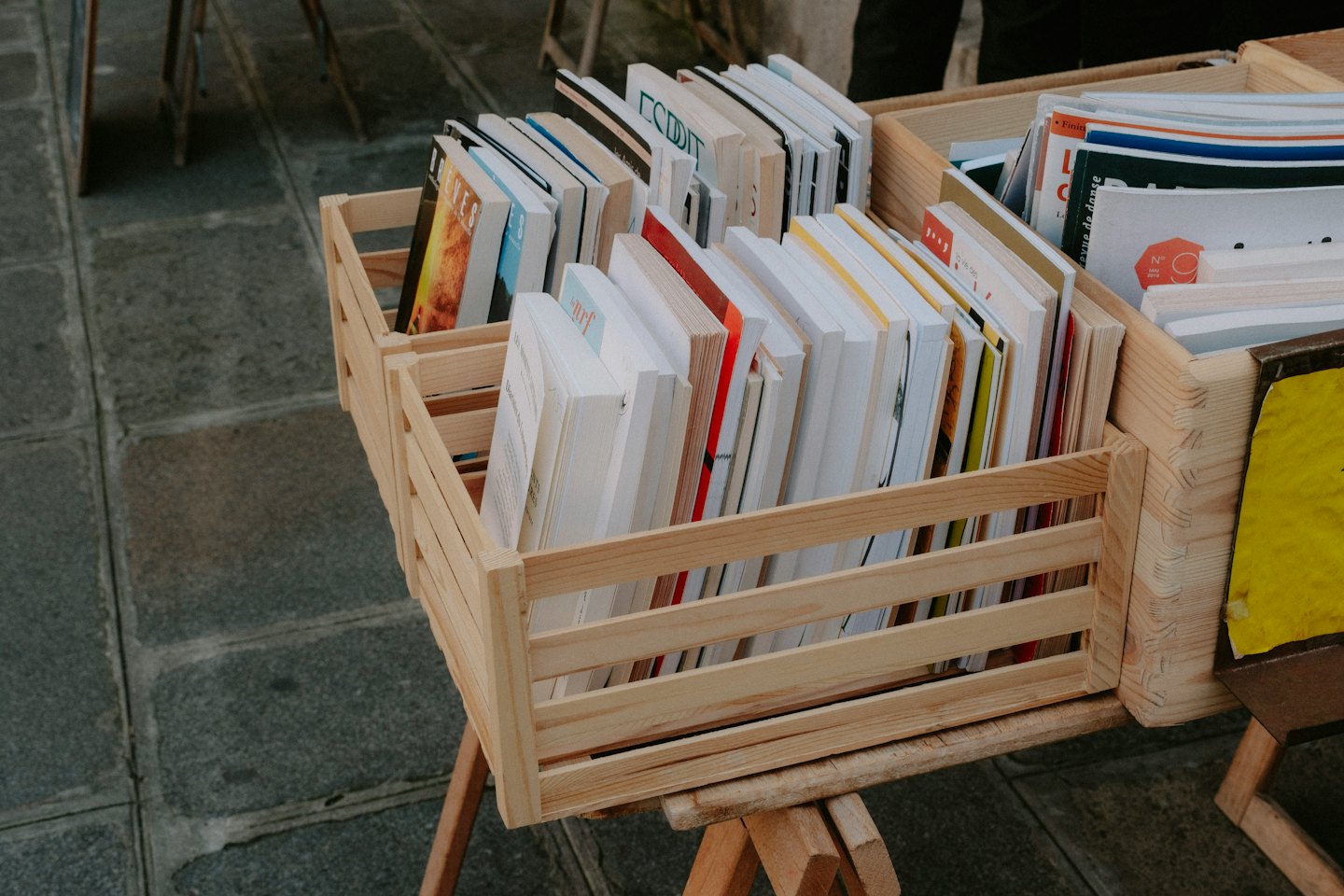 Libri colorati esposti in cassette di legno su un banco del mercato.