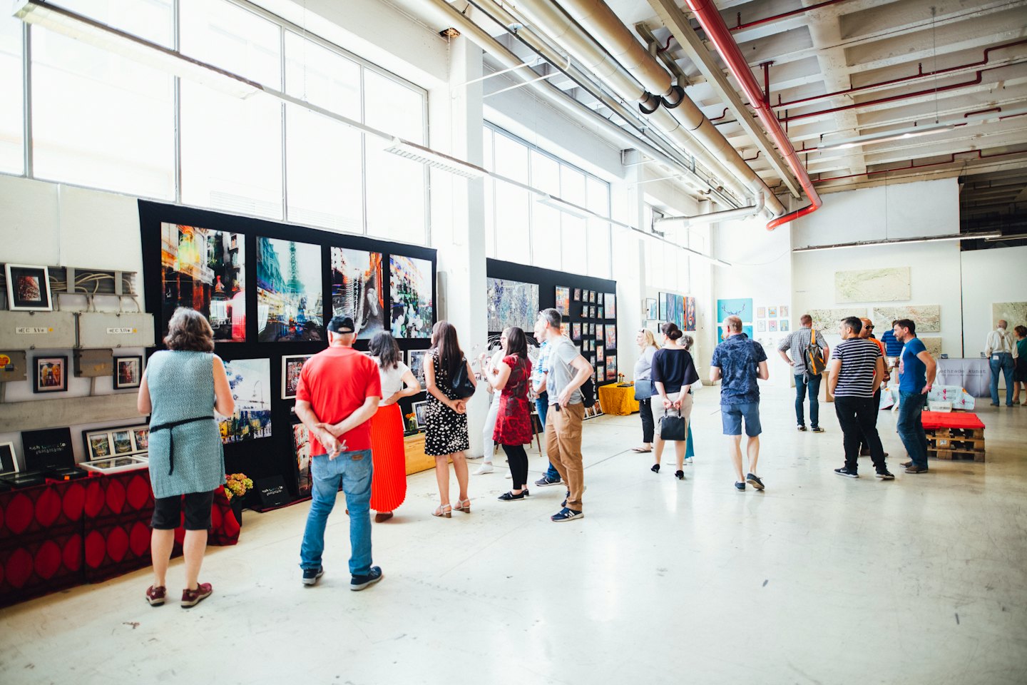 Persone che ammirano quadri e fotografie in una galleria d'arte moderna.